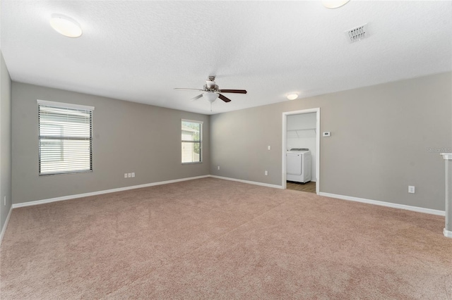 empty room featuring ceiling fan, light colored carpet, a textured ceiling, and washer / dryer