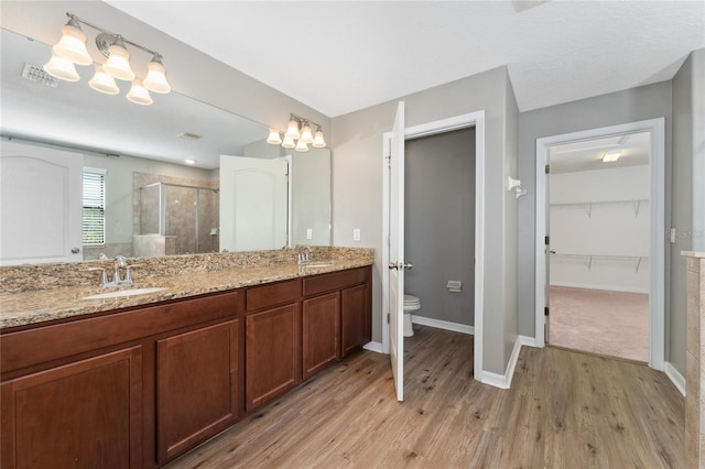 bathroom featuring wood-type flooring, vanity, toilet, and a shower with shower door