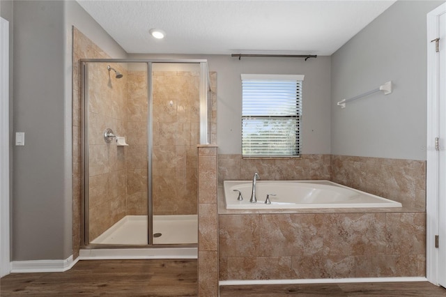 bathroom featuring hardwood / wood-style floors, shower with separate bathtub, and a textured ceiling