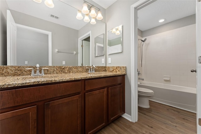 full bathroom featuring hardwood / wood-style floors, vanity, toilet, and tiled shower / bath