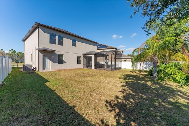 back of house featuring a lanai, central air condition unit, and a lawn