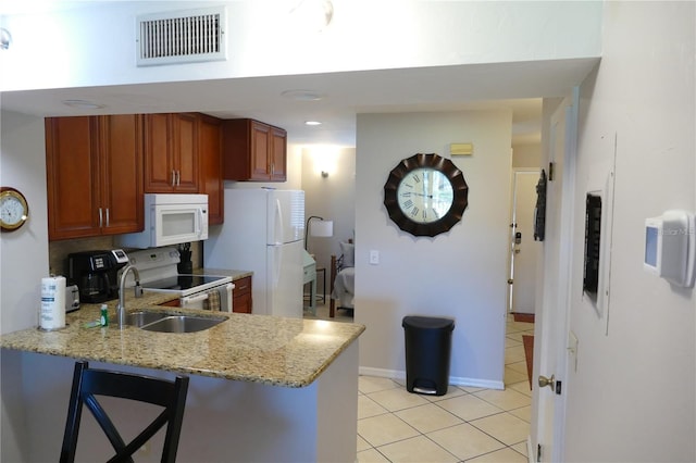 kitchen with sink, light stone counters, light tile patterned floors, kitchen peninsula, and white appliances