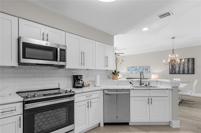 kitchen with kitchen peninsula, white cabinetry, sink, and stainless steel appliances