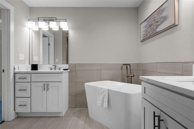 bathroom with vanity, a bath, and tile walls