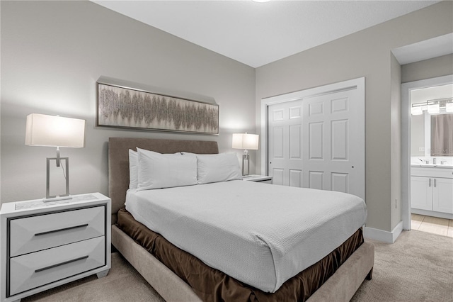 bedroom featuring light carpet, ensuite bathroom, and a closet