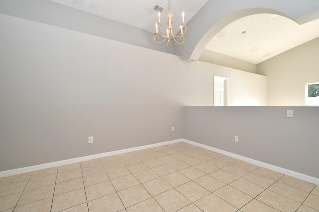 tiled spare room with vaulted ceiling and an inviting chandelier