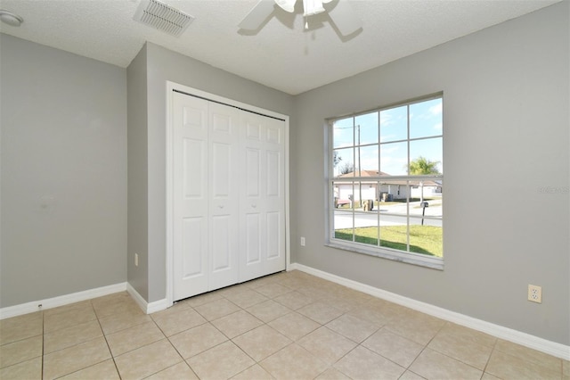 unfurnished bedroom featuring ceiling fan, light tile patterned floors, multiple windows, and a closet