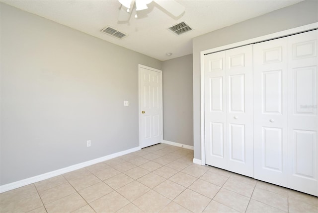 unfurnished bedroom featuring ceiling fan, a closet, and light tile patterned floors