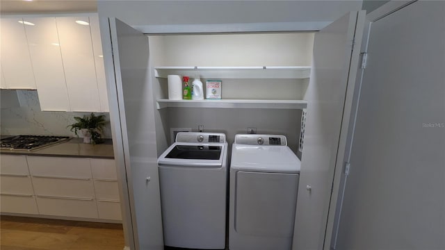 clothes washing area with independent washer and dryer and light hardwood / wood-style flooring