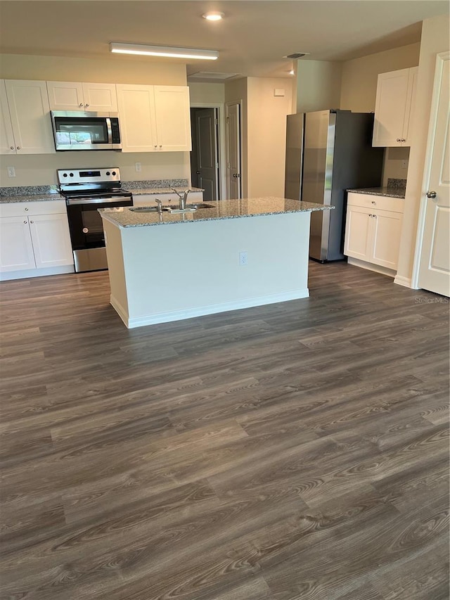 kitchen with stainless steel appliances, dark wood-type flooring, sink, white cabinets, and an island with sink