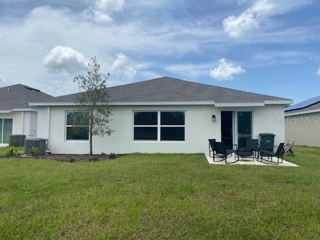 back of property featuring a lawn, central air condition unit, and a patio