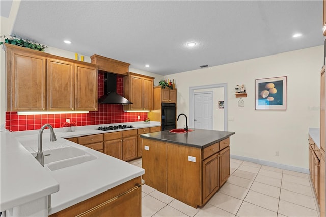 kitchen featuring white gas stovetop, backsplash, a kitchen island with sink, sink, and wall chimney exhaust hood