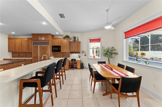 tiled dining room featuring ceiling fan, sink, and a textured ceiling