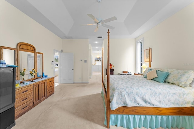 carpeted bedroom featuring a tray ceiling and ceiling fan