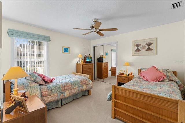 bedroom featuring ceiling fan, a closet, and light colored carpet