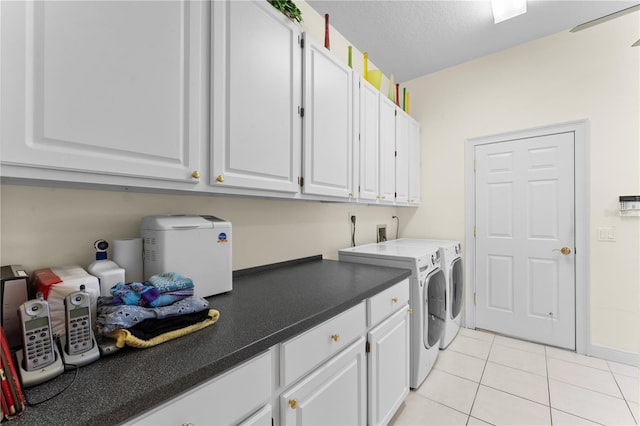 laundry room featuring cabinets, light tile patterned floors, a textured ceiling, and washing machine and dryer