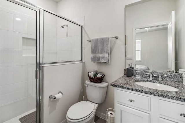 bathroom with vanity, a shower with shower door, and toilet