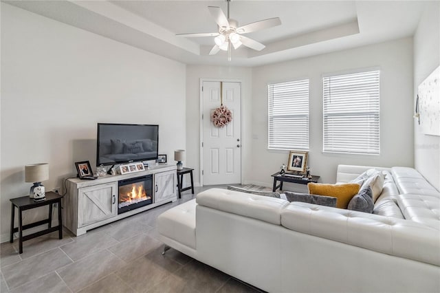 living room with a raised ceiling and ceiling fan