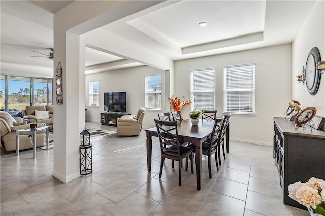 dining room with ceiling fan and a tray ceiling