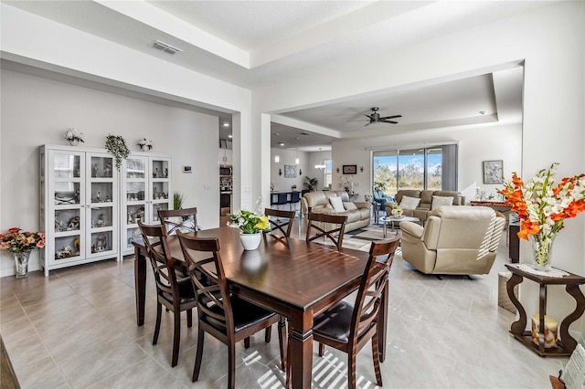 dining room with ceiling fan and a tray ceiling