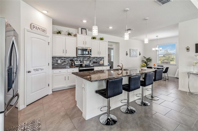 kitchen featuring appliances with stainless steel finishes, a center island with sink, white cabinetry, and sink