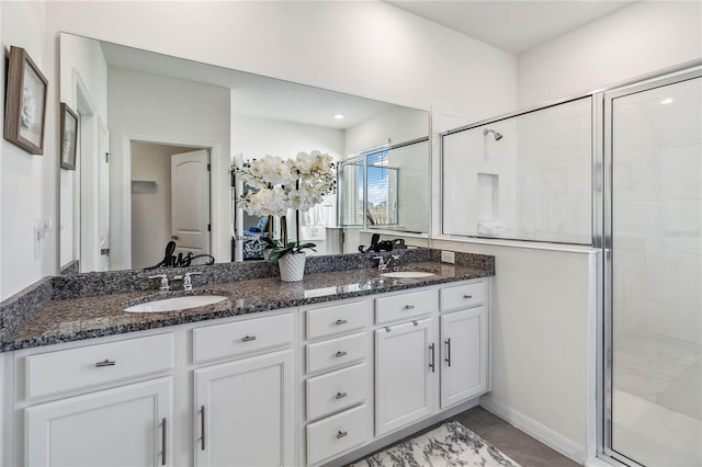 bathroom with a shower with door, vanity, and tile patterned flooring