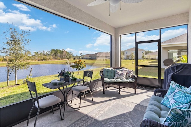 sunroom with ceiling fan and a water view