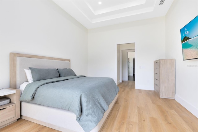 bedroom featuring a tray ceiling and light hardwood / wood-style flooring