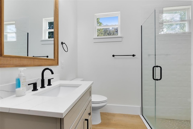 bathroom with toilet, hardwood / wood-style flooring, a shower with door, and vanity