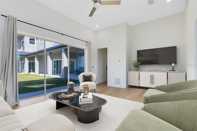 living room with light wood-type flooring, ceiling fan, and a wealth of natural light