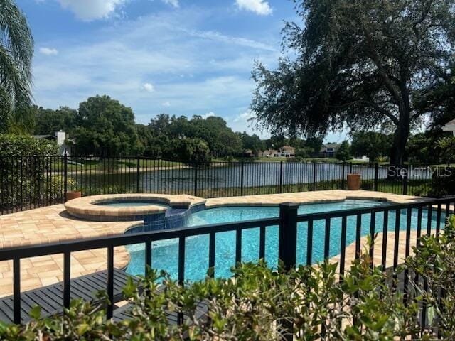 view of swimming pool featuring an in ground hot tub and a water view