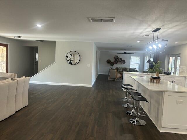 kitchen featuring a kitchen breakfast bar, dark wood-type flooring, a center island, white cabinetry, and hanging light fixtures