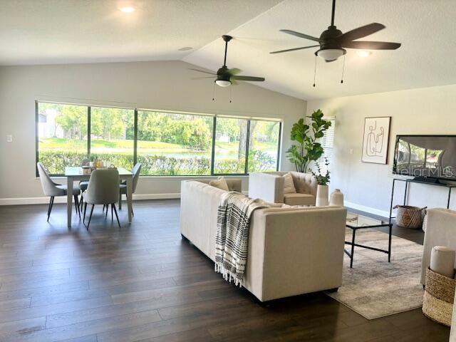 living room with dark hardwood / wood-style floors, ceiling fan, and lofted ceiling