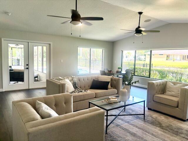 living room featuring hardwood / wood-style flooring, ceiling fan, lofted ceiling, and french doors