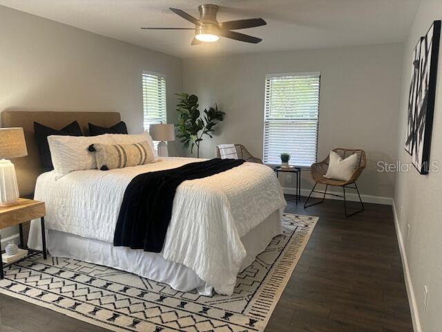 bedroom featuring ceiling fan, dark hardwood / wood-style flooring, and multiple windows