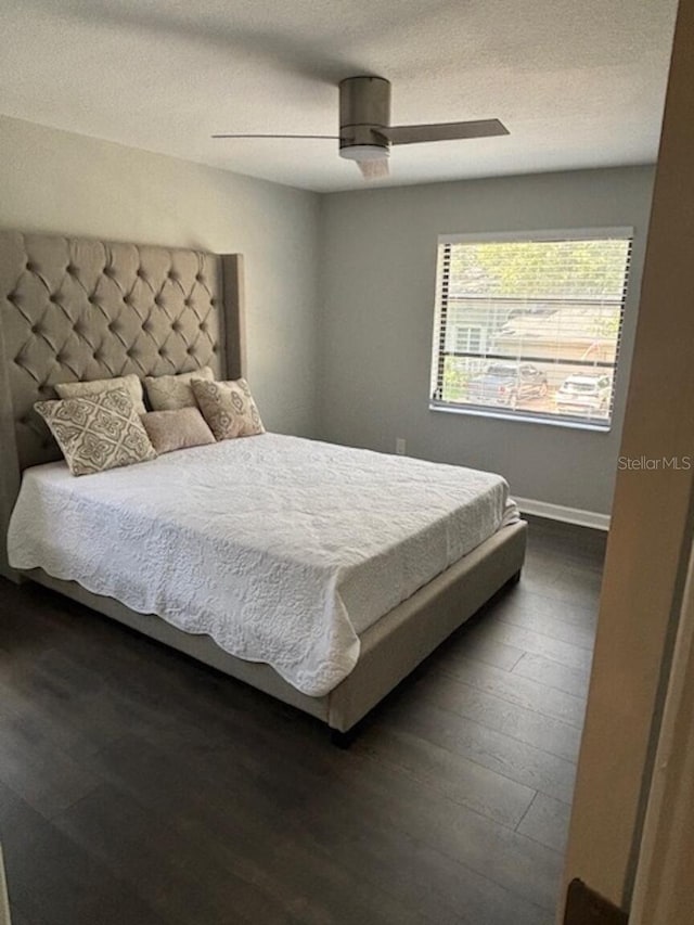 bedroom featuring a textured ceiling, ceiling fan, and dark wood-type flooring