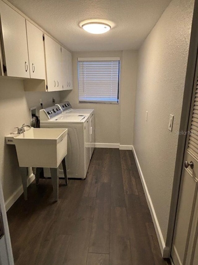 clothes washing area with cabinets, dark wood-type flooring, sink, a textured ceiling, and washing machine and clothes dryer