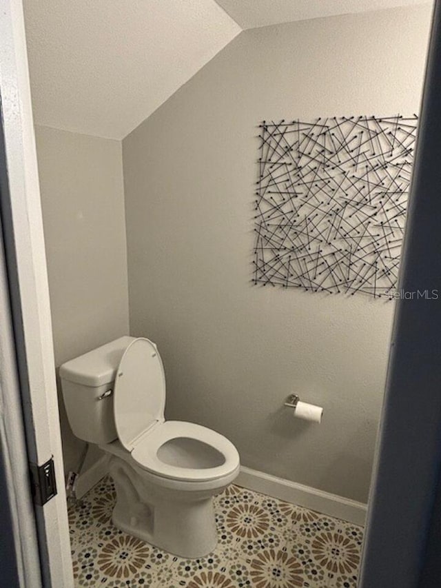 bathroom featuring tile patterned floors, toilet, and lofted ceiling