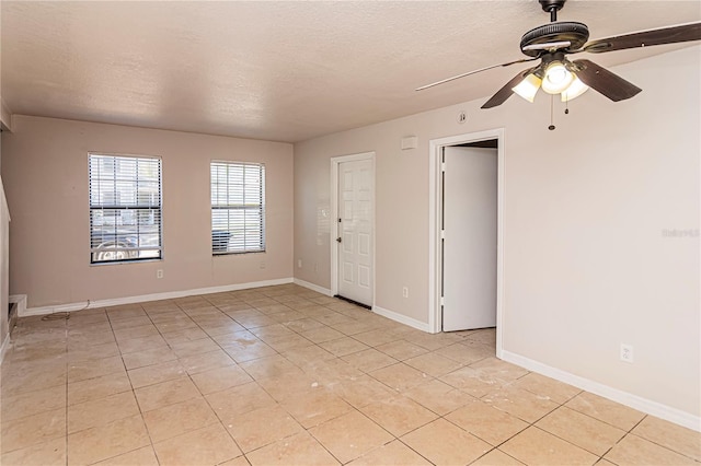 spare room with ceiling fan, light tile patterned flooring, and a textured ceiling