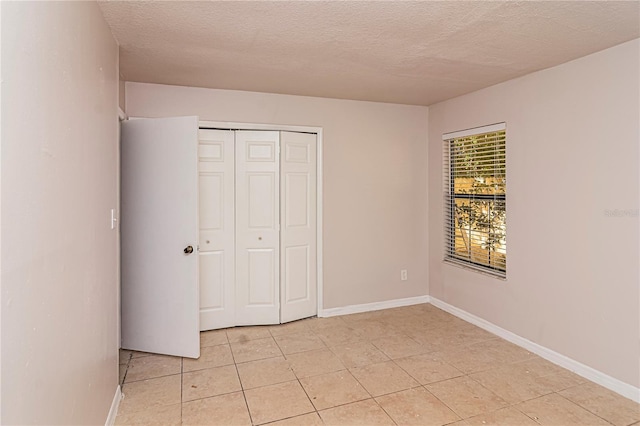 unfurnished bedroom with a textured ceiling, a closet, and light tile patterned floors