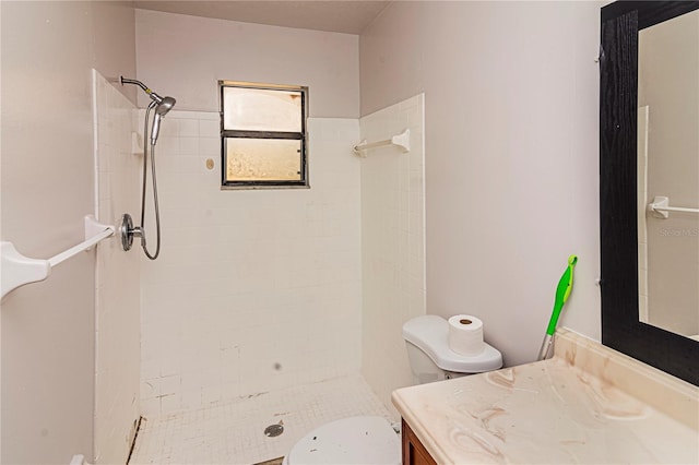 bathroom featuring a tile shower, vanity, and toilet