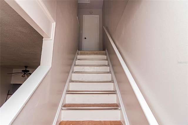 staircase featuring ceiling fan