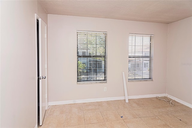 empty room featuring light tile patterned flooring and a textured ceiling