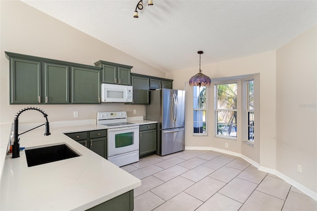 kitchen with sink, green cabinets, pendant lighting, vaulted ceiling, and white appliances