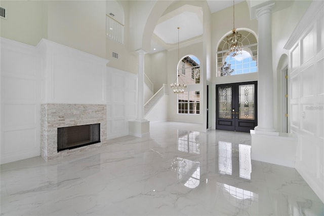 foyer with a fireplace, french doors, a notable chandelier, and a high ceiling