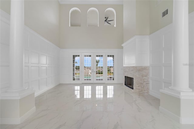 unfurnished living room featuring a tile fireplace, french doors, and a towering ceiling