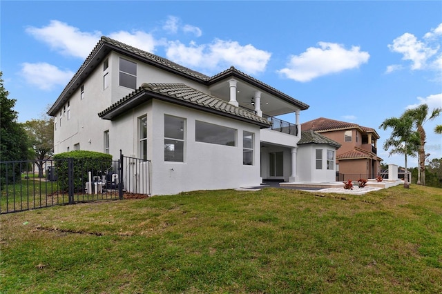 back of house with a balcony, a patio area, and a lawn