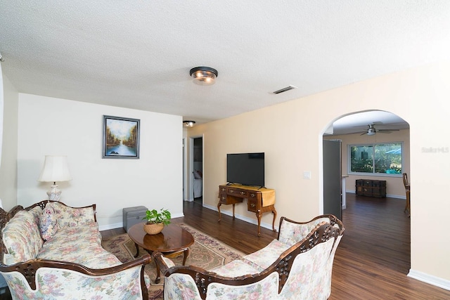 living room featuring ceiling fan, dark hardwood / wood-style flooring, and a textured ceiling