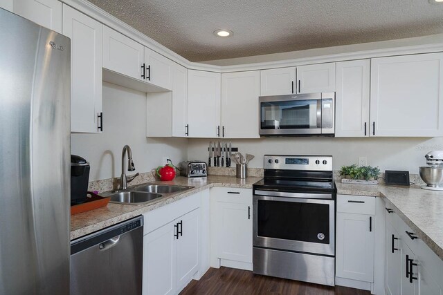 kitchen with white cabinetry, sink, dark wood-type flooring, stainless steel appliances, and a textured ceiling