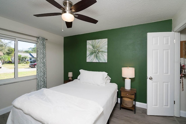 bedroom with ceiling fan, wood-type flooring, and a textured ceiling